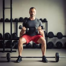 Man performing a focused dumbbell lift in a gym, representing the cognitive benefits of strength training on executive function.